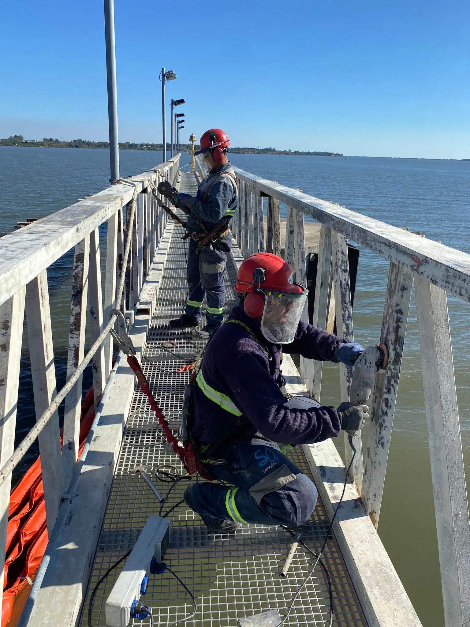Personal de SG trabajando sobre una pasarela junto al río